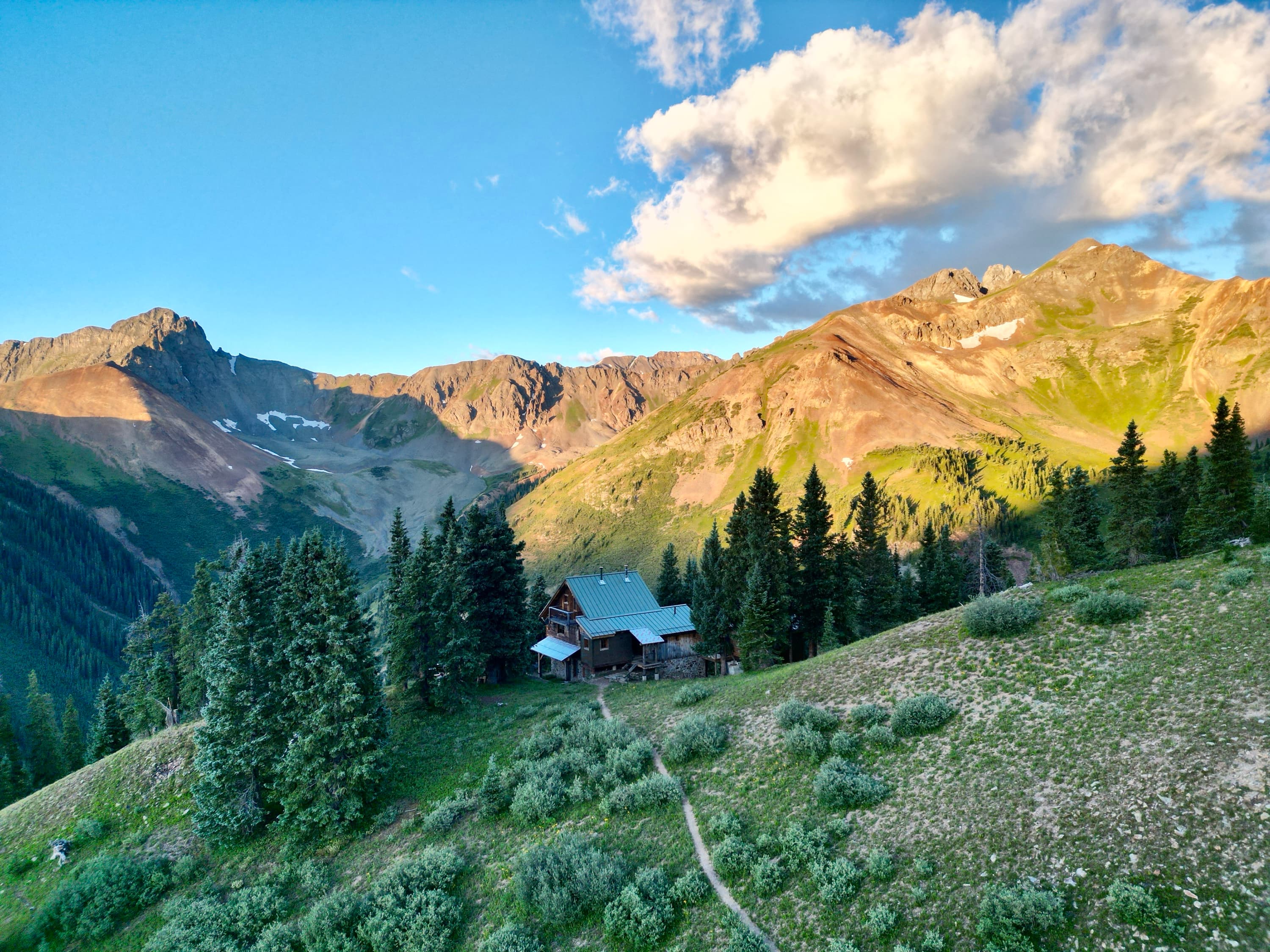 The OPUS Hut above a summer meadow at 11,765 feet
